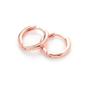Close-up of polished rose gold hoop earrings featuring a minimal huggie buckle design