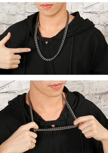 Detail of a vintage titanium steel NK chain worn by a male model against a brick wall