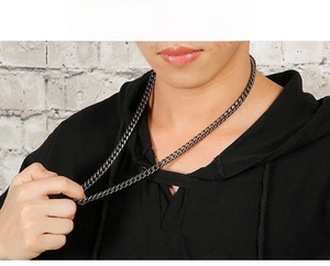 Close-up of black matte titanium steel Cuban link chain necklace on male model