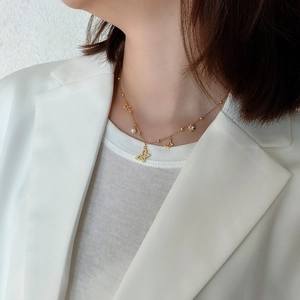 Detail of gold butterfly necklace with pearls and zircons worn on a model's neck