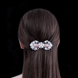 Elegant gold hair clip with pearls and rhinestones on a model against black background
