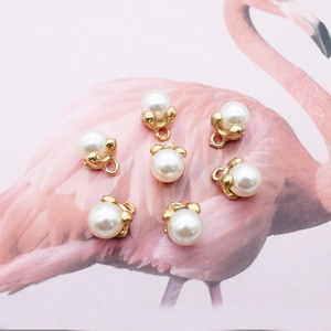 Seven white pearl pendants with gold alloy bases displayed on a pink flamingo background