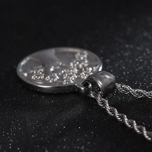 Macro shot of silver stainless steel Tree of Life pendant with a twisted rope chain