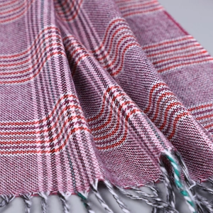 Vue détaillée de la texture tissée à carreaux et franges bicolores sur une écharpe d'hiver