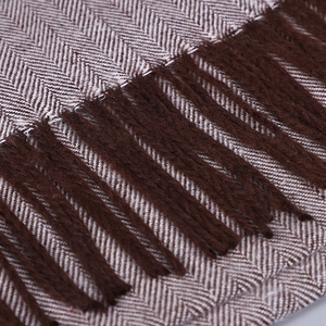Gros plan sur le tissu à chevrons avec de longs pompons marrons sur une écharpe