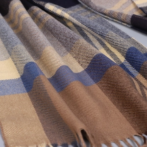 Gros plan d'une écharpe épaisse à carreaux en sergé bleu, marron et beige avec franges