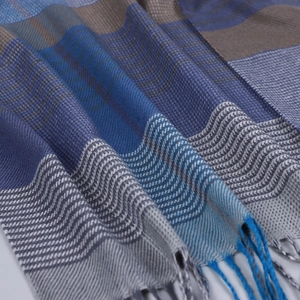 Détail de l'écharpe à rayures bleu et gris avec texture tissée douce et franges