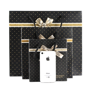 Three assorted sizes of black gift bags with gold polka dots and champagne bows