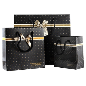 Three-piece black gift bag set with gold polka dots and decorative ribbon bows