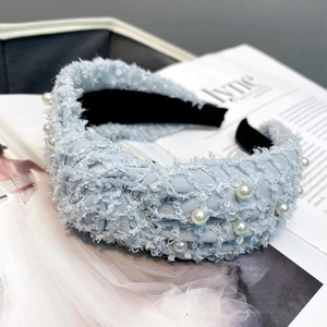 Detailed view of a blue feather yarn headband with white pearl accents and soft lining