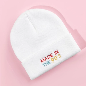 Close-up of MADE IN THE 90'S colorful embroidery on white knitted beanie hat texture