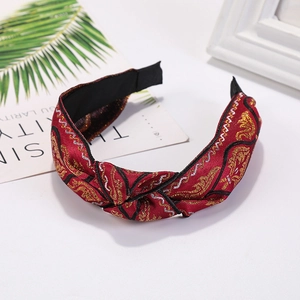 Close-up of red fabric knotted headband with intricate gold floral embroidery details