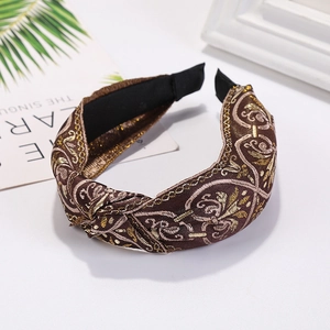 Detailed view of bronze knotted headband featuring intricate golden embroidery patterns