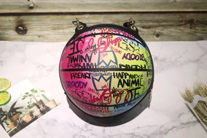 Close-up of graffiti basketball-shaped bag with gradient colors on marble background