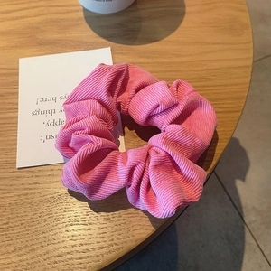 Close-up of pink corduroy hair scrunchie on wood table with aesthetic card background