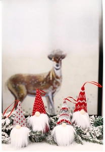Set of four knitted Christmas gnomes with heart patterns and plush white beards on snow