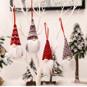 Detail of knitted Christmas gnomes with long white beards hanging on white branches