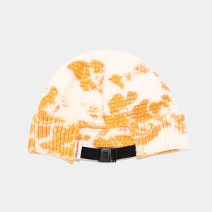 Detail view of tie-dye knit beanie featuring adjustable black strap and brand label