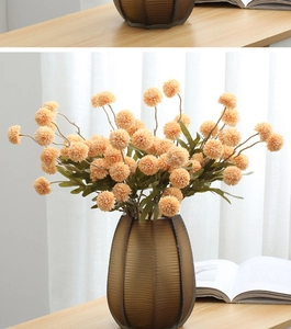 Close-up of orange artificial pompon chrysanthemums in a brown ribbed glass vase