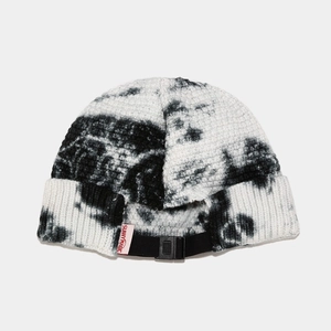 Detail view of tie-dye knit beanie featuring adjustable black strap and red woven label