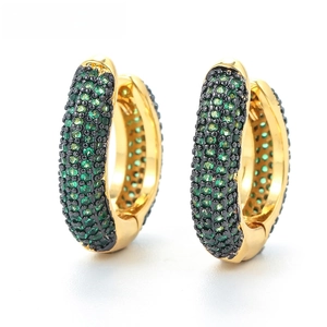 Detail of gold huggie earrings with pave emerald green zircons and hinge closure