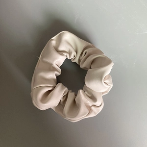 Close-up of beige PU leather scrunchie with a soft textured finish and elegant design