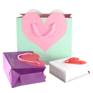 Three sizes of heart patterned gift bags in mint, purple, and white with love prints