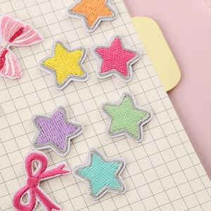 Colorful embroidered star and bow patches scattered on a grid notebook for DIY decor