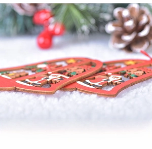 Side view of laser-cut wooden Christmas bell ornaments with festive painted scenes