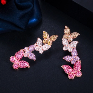 Macro shot of rose gold butterfly earrings with pink and purple zircon crystals