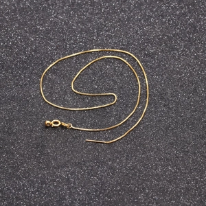 Golden skeleton face pendant necklace with thin chain on black background
