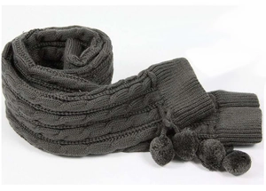 Close-up of dark grey cable knit leg warmers featuring decorative pom-poms on white background