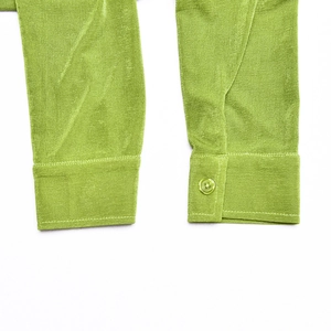 Close-up of green cardigan cuffs with button detail and velvet texture fabric