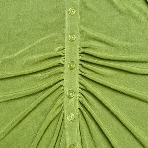 Macro shot of bright green knit fabric detailing with ruched design and matching buttons