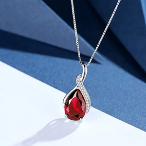 Detailed macro view of an elegant teardrop ruby pendant with silver crystal setting