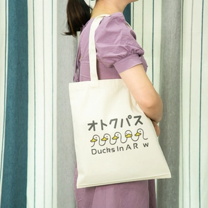 Detail view of cream canvas tote bag featuring cute duck graphics and Japanese text
