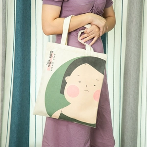 Detail of beige canvas tote bag with cartoon print and reinforced stitched handles