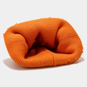 Detailed macro view of vibrant orange ribbed knit beanie showing thick texture and frayed edges