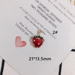Detailed macro view of a red strawberry alloy pendant with green leaves and gold ring