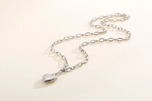 Macro shot of 3D silver heart pendant on an oval link chain with a polished metallic finish