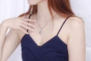 Close-up of minimalist silver heart necklace worn on a model against white fabric