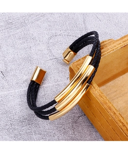Close-up of multilayer braided leather bracelet with golden metal cylinders and clasp