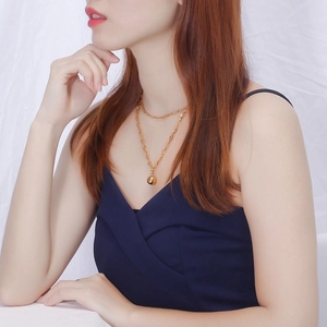 Elegant gold double-layered necklace with round bead pendant shown on a model