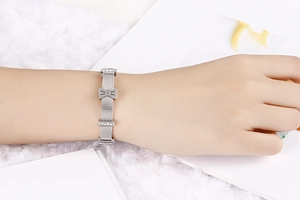Détail d'un bracelet en maille argentée avec nœud en strass porté sur le poignet