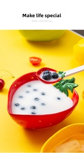 Detailed close-up of a creative strawberry-shaped ceramic bowl and spoon set on yellow