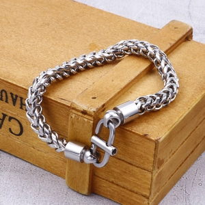 Detail of silver stainless steel dragon chain bracelet with retro clasp on a wooden box