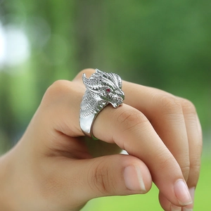 Detailed close-up of a silver dragon head ring featuring intricate scales and red gemstone eyes
