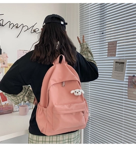 Zaino in nylon rosa con ciondolo a forma di cucciolo bianco visto dal retro con stile