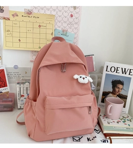 Zaino rosa minimalista con ciondolo a forma di cucciolo di peluche su scrivania