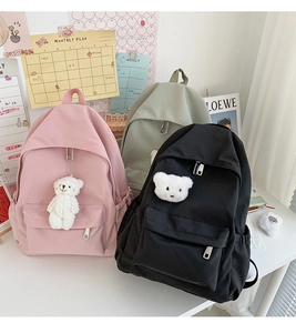 Dettaglio di zaini in nylon nei colori rosa, nero e verde con ciondoli a forma di orso